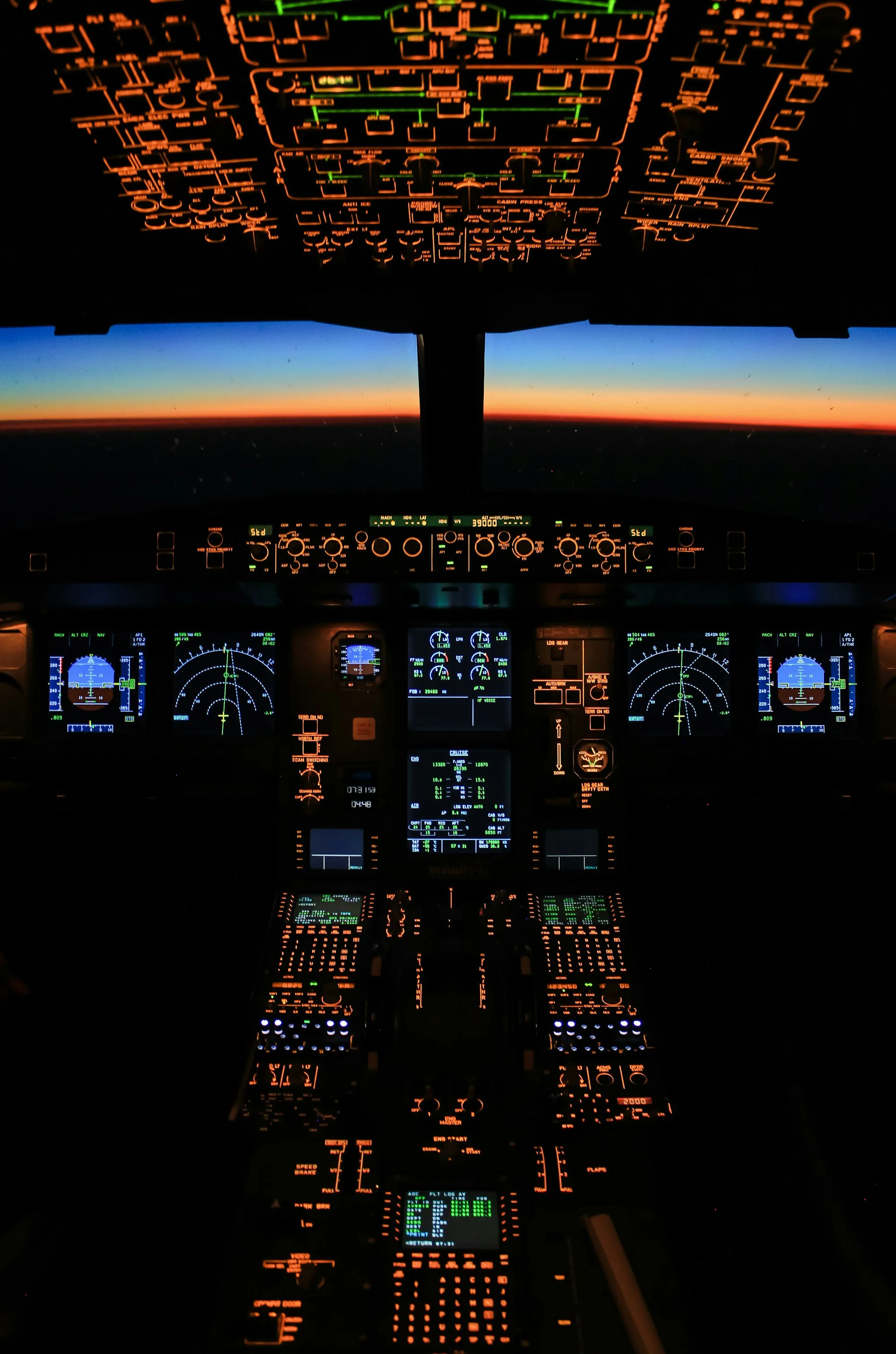 Airliner cockpit at night with the instruments lit and dawn on the horizon